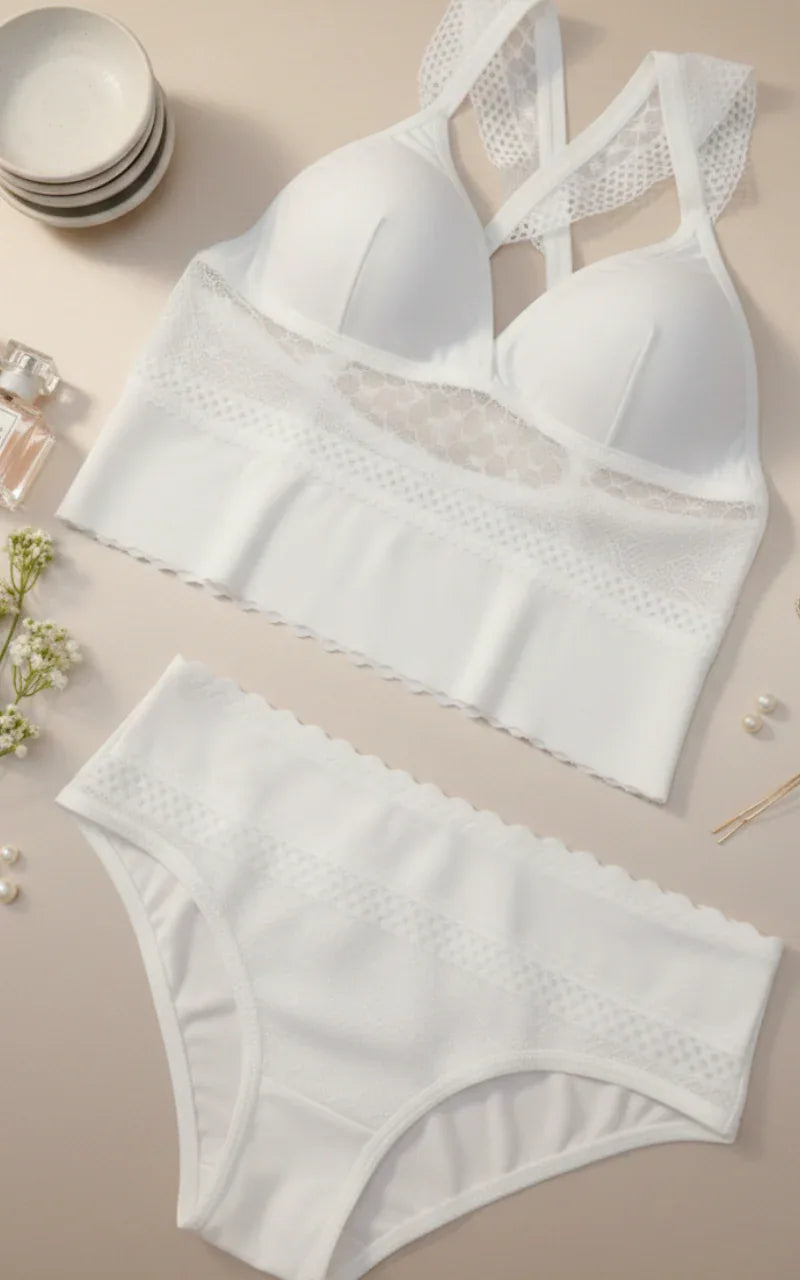 White lace-trimmed bra and panties set on a beige surface with decorative items.